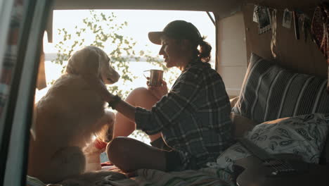 Female-Tourist-Having-Tea-while-Sitting-with-Dog-in-Van-at-Sunset